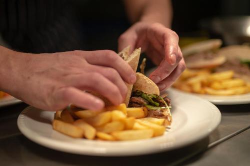 a person holding a sandwich and french fries on a plate at Grant Arms Hotel in Grantown on Spey