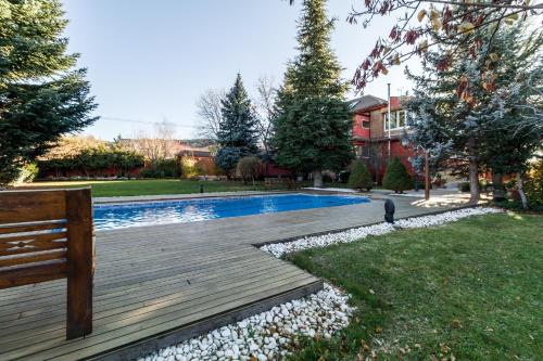 a backyard with a wooden deck and a swimming pool at B&B Concha in Becerril de la Sierra