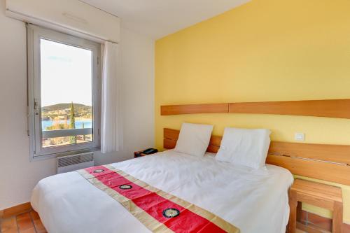 Schlafzimmer mit einem großen Bett und einem Fenster in der Unterkunft Village Club Les Mas de L'Esterel in Agay - Saint Raphael