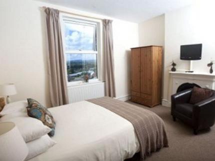 een slaapkamer met een bed, een stoel en een raam bij The Mount Guest House in Ludlow