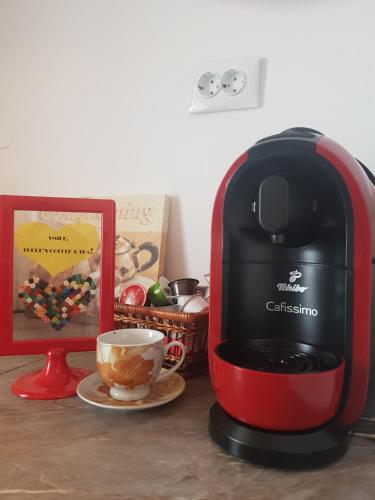 a red coffee maker sitting on a table next to a cup at Relax Apartament in Constanţa