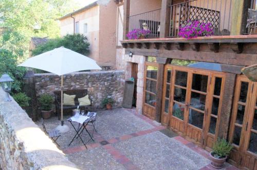 a patio with an umbrella and a table with a chair at Hotel Rural El Adarve in Ayllón
