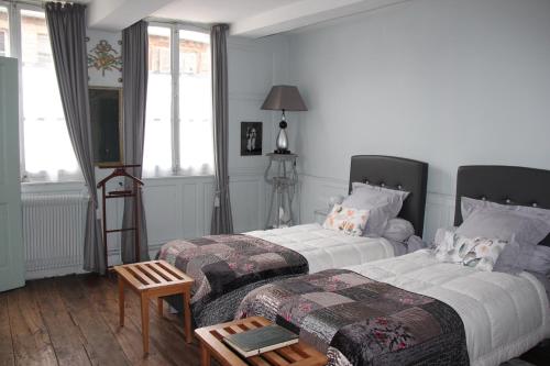 1 dormitorio con 2 camas y mesa en Les Capucines, en Abbeville