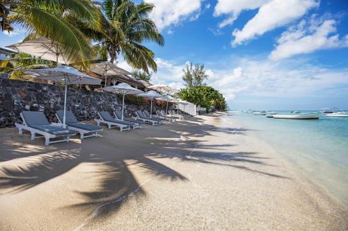 a beach with chairs and umbrellas and the ocean at The Bay in Rivière Noire