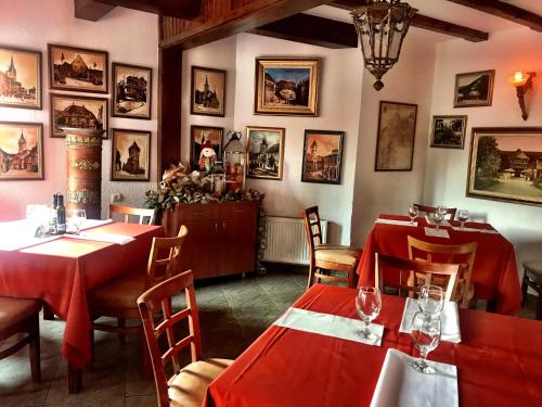 a restaurant with red tables and chairs and pictures on the walls at Pensiunea Apfelhaus in Cisnadioara