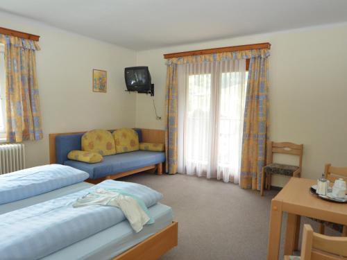 a bedroom with two beds and a couch and a tv at Gästehaus Golker in Bad Gastein