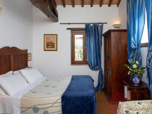 a bedroom with a bed and a window with blue curtains at Al Guado di Assisi B&B in Bastia Umbra