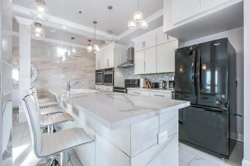 a kitchen with white cabinets and a black refrigerator at Stunning Penthouse in the Heart of the City in New Orleans