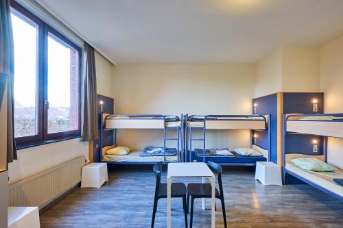 a room with three bunk beds and a table and chairs at Generation Europe Youth Hostel in Brussels