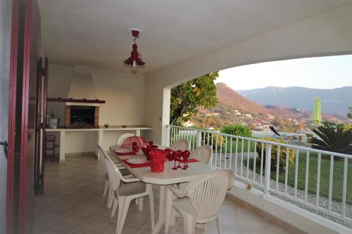 a dining room with a table and chairs on a balcony at Résidence U MELU GRAND T3 ROUGE en rez de jardin in Tiuccia