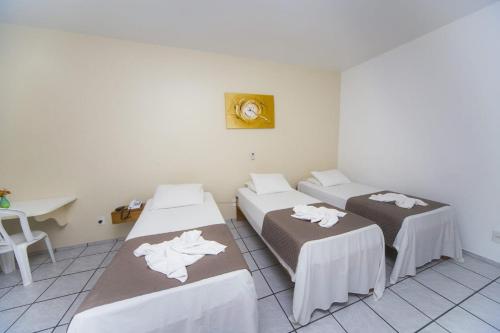 a room with three beds and a table and a desk at Hotel Rekinte in Aracaju