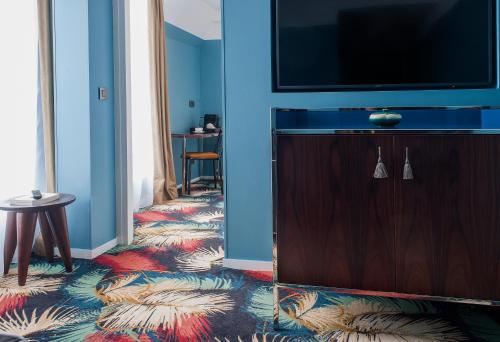 a living room with a television and a floor with a rug at Hotel Eiffel Blomet in Paris