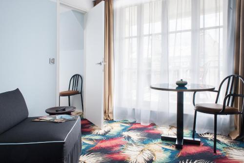 d'un salon avec une table, des chaises et une fenêtre. dans l'établissement Hotel Eiffel Blomet, à Paris