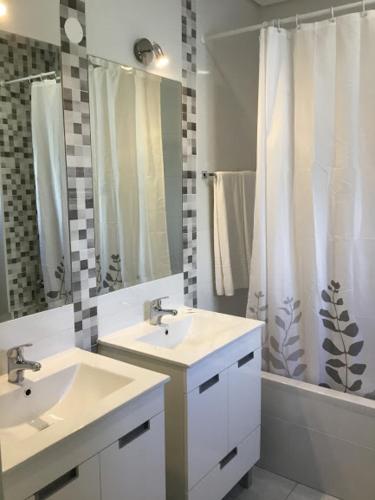 um banheiro com duas pias e uma cortina de chuveiro em Prado do Golf em Vilamoura