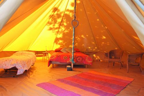 une tente avec un lit, des chaises et un tapis dans l'établissement Camping Bois de St Hilaire, à Chalandray