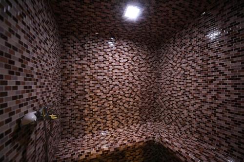 a bathroom with a brown brick wall with a shower at Hotel Slodes in Belgrade