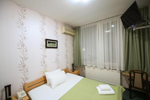 a small room with a white bed and a window at Hotel Slodes in Belgrade