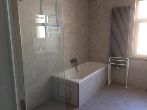a bathroom with a bath tub and a shower at Maison au calme à 300m de la plage in De Panne