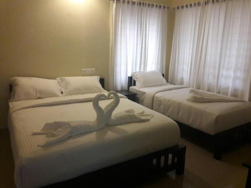 two swans made out of towels on two beds at White Petals -3 BHK Homestay Munnar - Available For Indian Nationals Only in Munnar