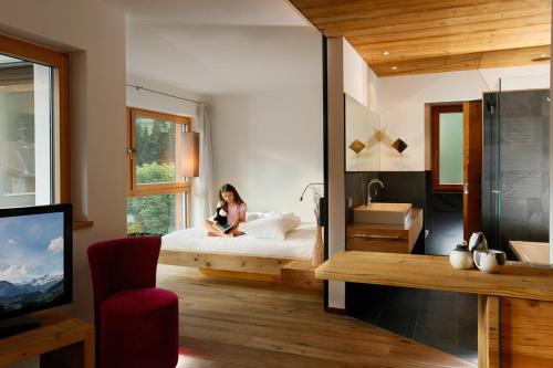 a woman sitting on a bed in a bedroom at Hotel Ratschingserhof in Racines