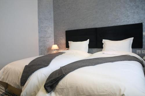 ein großes Bett mit weißen Laken und einem schwarzen Kopfteil in der Unterkunft Point du Jour in Casablanca