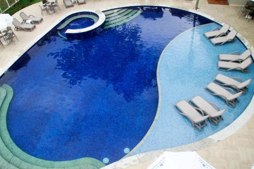 a swimming pool with a blue and white pool table and chairs at Beach Hotel Sunset in Camburi