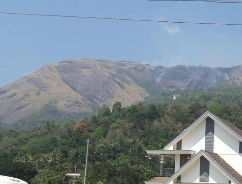 a white house with a mountain in the background at White Petals -3 BHK Homestay Munnar - Available For Indian Nationals Only in Munnar