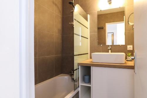 La salle de bains est pourvue d'un lavabo, d'une baignoire et d'un miroir. dans l'établissement Apartment Chamois Blanc 7A, à Chamonix-Mont-Blanc