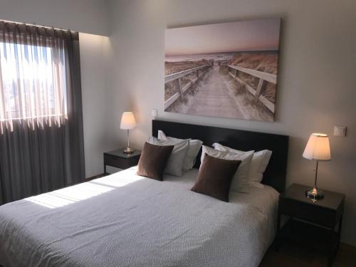 a bedroom with a large white bed with two lamps at Vasco da Gama in Póvoa de Varzim