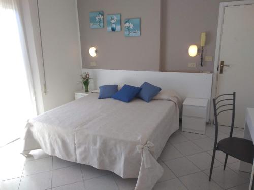 a bedroom with a large white bed with blue pillows at Hotel La Bella Vita in Rimini