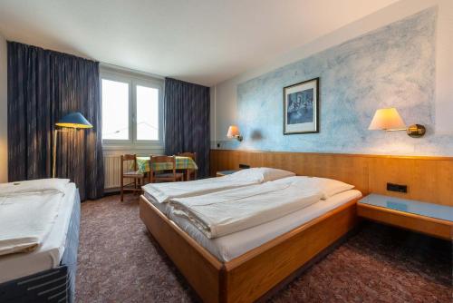 a hotel room with two beds and a table at enjoyHotel garni Korntal Stuttgart in Stuttgart