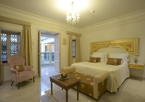 a bedroom with a bed and a chair and a table at Dar ALOUINI in Kairouan
