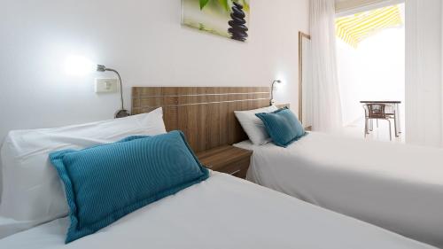 2 Betten mit blauen Kissen im Schlafzimmer in der Unterkunft Armonía Beach 15 in Arinaga