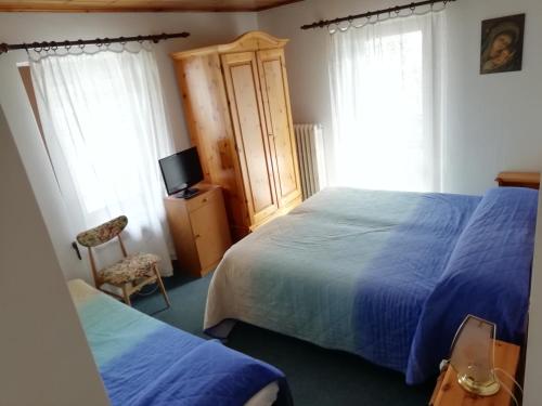 una camera con due letti e una TV e due finestre di ALBERGO SORGENTI DEL PIAVE a Sappada