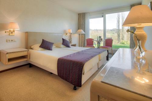 een slaapkamer met een bed, een tafel en een raam bij Hotel & Appartement de Zevende Heerlijkheid in Slenaken