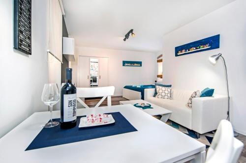 a living room with a white table with a bottle of wine at Studio Biritin in Rovinj