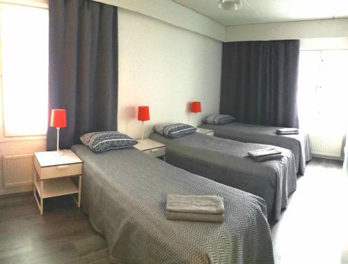 two beds in a room with blue curtains at Hamina Orange Apartments Ilves in Hamina