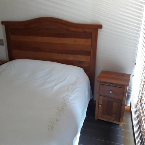 a bedroom with a bed and a wooden night stand at Departamento Lago Vichuquen in Lago Vichuquen