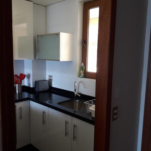 a kitchen with white cabinets and a sink and a window at Departamento Lago Vichuquen in Lago Vichuquen