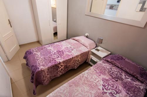 コスタ・デル・シレンチオにあるCasa Mariposaの小さな部屋のベッド2台 紫色のシーツ付