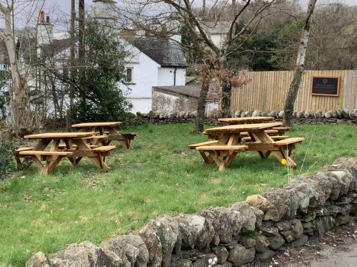 a row of wooden benches sitting on top of a grass covered field at The Sun Inn in Windermere