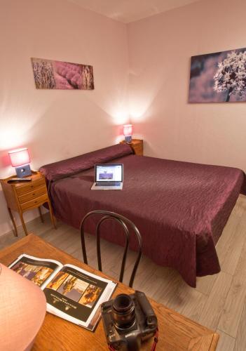 a hotel room with a bed and a table with a laptop at Le Signoret in Sault-de-Vaucluse