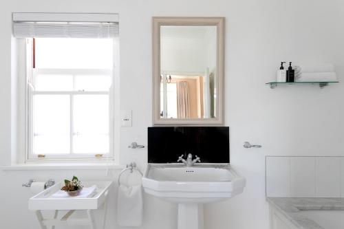 a white bathroom with a sink and a mirror at De Zalze Winelands Golf Lodge 6 in Stellenbosch