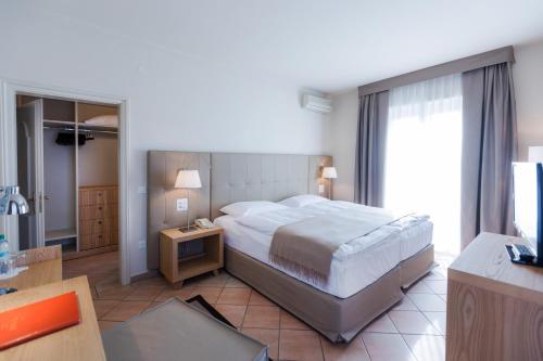a bedroom with a large bed and a desk and a table at Parkhotel Delta, Wellbeing Resort in Ascona