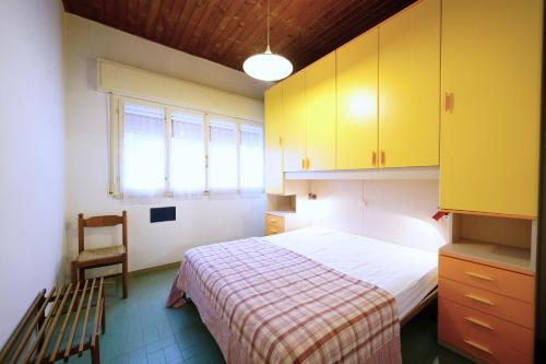 a bedroom with a bed and a chair and yellow cabinets at Villetta 2C in Lido degli Estensi