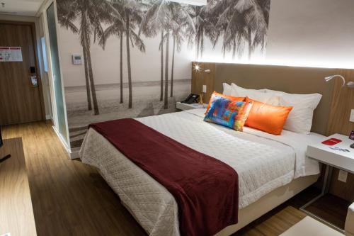 a bedroom with a bed with palm trees on the wall at Rio Hotel by Bourbon Ciudad Del Este in Ciudad del Este