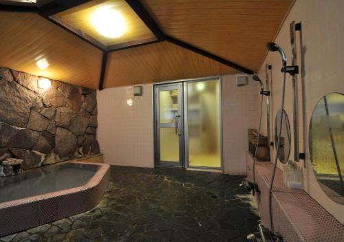 uma grande casa de banho com banheira e uma parede de pedra em Address Nozawa Japanese Room / Vacation STAY 22751 em Nozawa Onsen