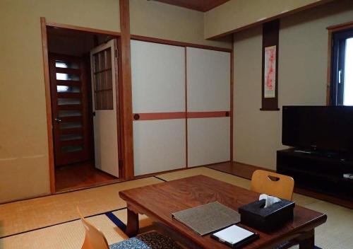 uma sala de estar com uma mesa e uma televisão em Address Nozawa Japanese Room / Vacation STAY 22751 em Nozawa Onsen