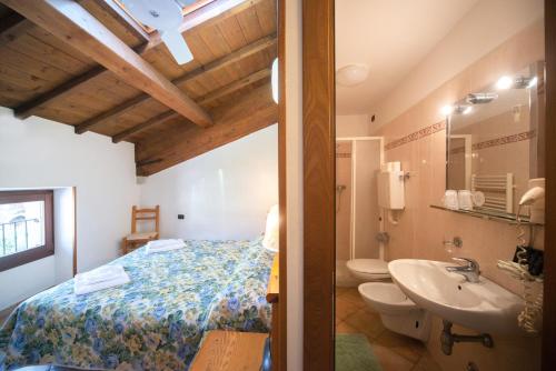 a bathroom with a bed and a sink and a toilet at Albergo Al Platano in Caprino Veronese