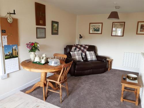 a living room with a table and a leather couch at Forest Farm Papplewick Nottingham - Spacious Self-Contained Rural Retreat! in Papplewick